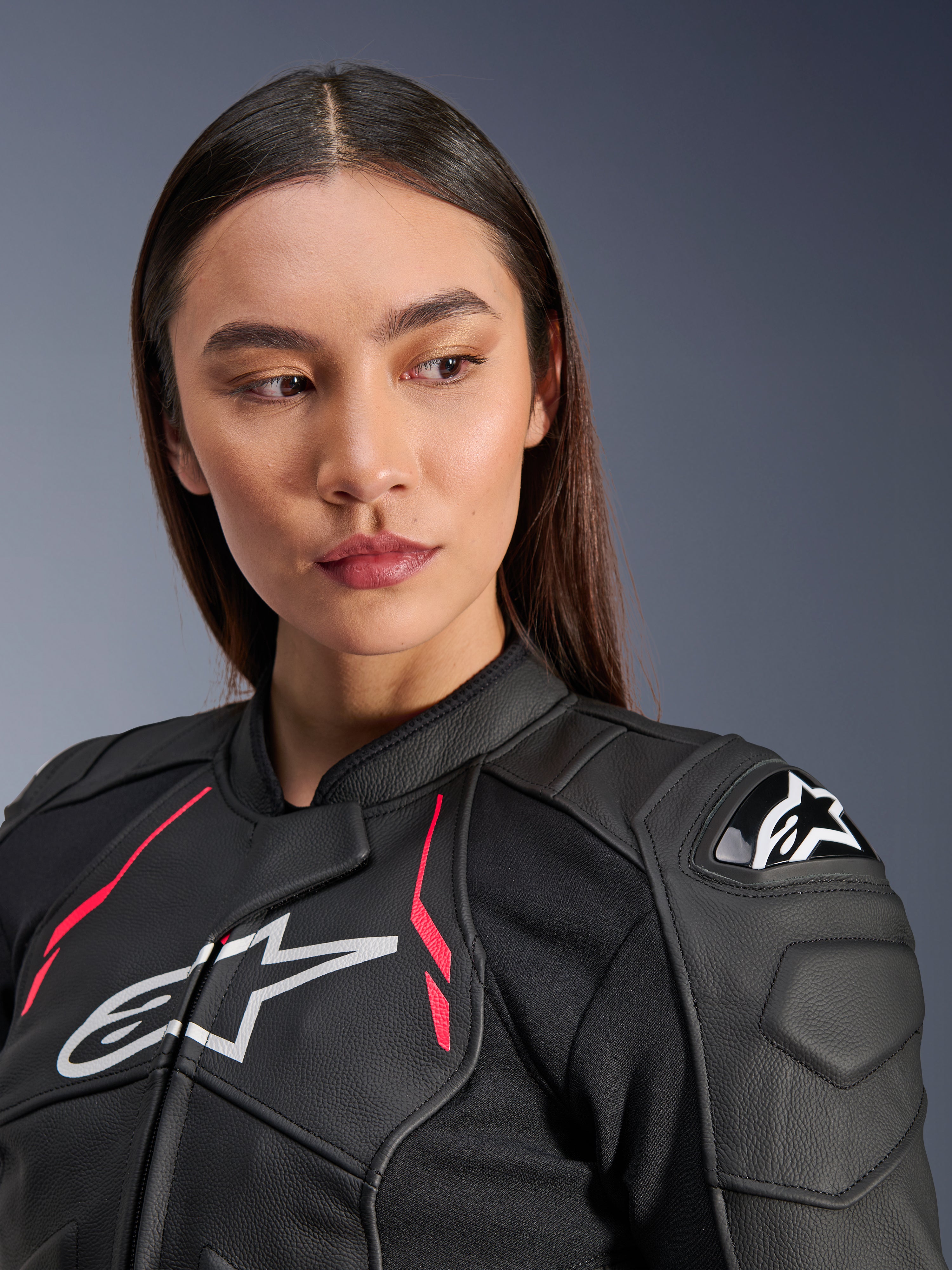 Kvinna som bär Alpinestars Stella Dusk läderjacka i Black Diva Pink White, med en vit bröstlogotyp, livfulla rosa accenter och externa DFS-axelskydd, motorcykelutrustning i premium nötlärder