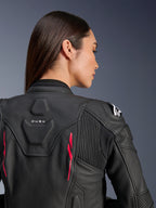 Kvinna som bär Alpinestars Stella Dusk läderjacka, svart läder med Diva Pink-detaljer och vit logotyp på axeln, vy bakifrån som visar DUSK-märkning och dragspelspaneler, sportig ergonomisk design