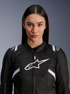 Kvinnlig modell som bär Alpinestars Stella T-SPS Air V2-jacka, motorcykeljacka för dam, svart och vit, med meshpaneler som andas och vit Alpinestars-logotyp på bröstet, sportig design för vägkörning