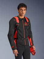 Alpinestars MM93 AMP3 Backpack, Red Fluo and Black, worn by a model with a matching black and red MM93 motorcycle jacket and gloves, front view highlighting the adjustable shoulder straps and chest buckle, technical racing-inspired gear.