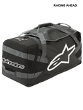Alpinestars Goanna Bag, motocross-duffelväska, svart och antracitgrå med vita logotyper, stor stjärnlogotyp på sidan och ordmärke, slitstark botten i presenning, förstärkta bärremmar, rymlig förvaring för utrustning för terrängkörning