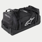 Alpinestars Komodo Travel Bag, stor utrustningsväska för motocross i svart och antracit med vita logotyper, utrustad med hjul och ett teleskophandtag, hållbar konstruktion för transport av racingutrustning