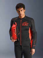 Man wearing Alpinestars MM93 Waist Bag, Red Fluo and Black, styled as a crossbody bag over a matching black and red motorcycle jacket, featuring Marc Marquez 93 logo, sporty racing design