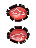 Alpinestars GP Tech knäsliders, röda och vita, knäskydd för motorcykelracing, med en stor vit stjärnlogotyp på blank röd plast, texten 'ONE GOAL. ONE VISION.' på svart blombladsformad kardborrebaksida, ett par för vänster och höger sida för banbruk.