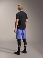 Alpinestars A-Aria Switch Jersey, kortärmad MTB-tröja, svart, baksida på modell med blå shorts och svarta knäskydd, teknisk cykelutrustning för stigcykling