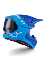 Alpinestars Supertech M10 Flood-hjälm, motocrosshjälm, ljusblå och marinblå med exponerad svart kolfiber, bakre sidoprofil som visar ventilationsöppningar och vit logotyp, rött innerfoder, avancerad aerodynamisk design för terrängprestanda
