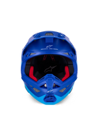 Alpinestars Supertech M10 Flood-hjälm ECE, motocrosshjälm, metallic- och mellanblå med svarta kolfiberdetaljer, vy framifrån som visar hakparti och ögonöppning, vita Alpinestars-logotyper och text, röd invändig vaddering, professionellt skydd för terrängkörning