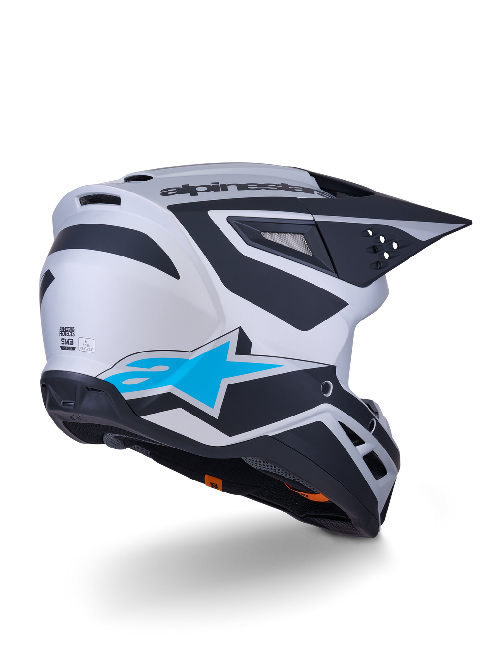 Alpinestars S-M3 Heat-hjälm ECE 22.06, motocrosshjälm, silver, blå och matt svart, vy bakifrån med stor blå stjärnlogotyp och svarta vinklade mönster, aerodynamiskt skal med ventilationsöppningar, högpresterande skydd för terrängkörning