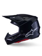 Alpinestars S-M7 Solid hjälm, blanksvart motocrosshjälm, sidoprofil som visar vit Alpinestars-logotyp, aerodynamiskt skal med ventilationsnät och röd invändig vaddering, avancerat skydd för terrängkörning