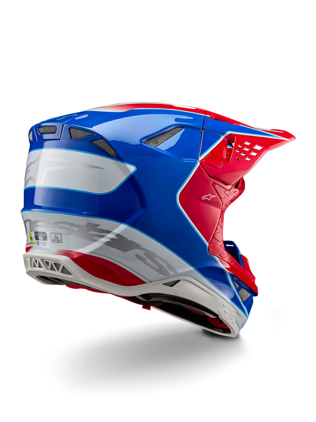 Alpinestars Supertech M10 Aeon ECE 22.06 hjälm, motocrosshjälm, röd, blå och vit i glansig finish, vy snett bakifrån med en aerodynamisk profil, silverfärgade Alpinestars-logotyper och integrerade ventilationsöppningar.