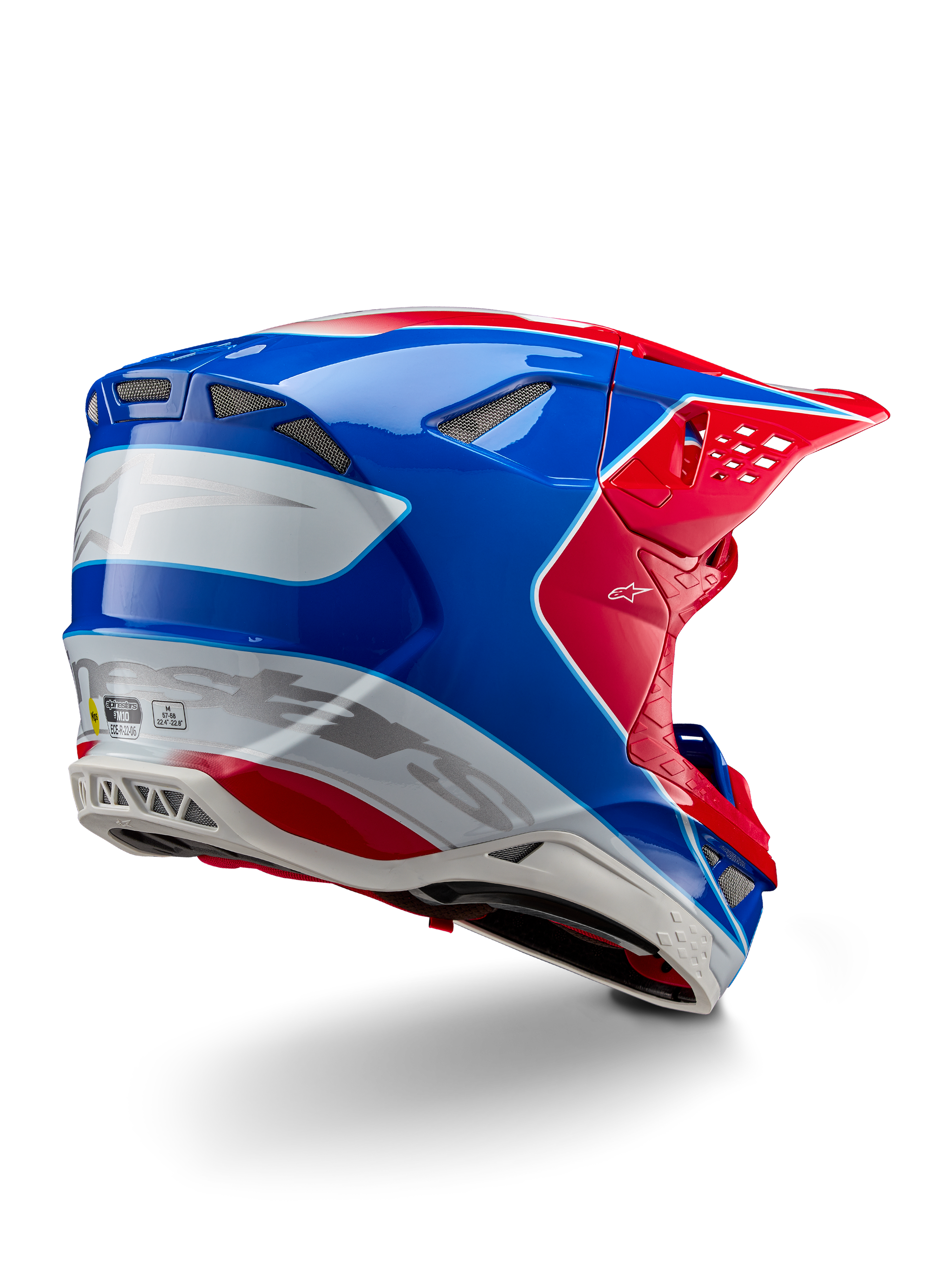 Alpinestars Supertech M10 Aeon ECE 22.06 hjälm, motocrosshjälm, röd, blå och vit i glansig finish, vy snett bakifrån med en aerodynamisk profil, silverfärgade Alpinestars-logotyper och integrerade ventilationsöppningar.