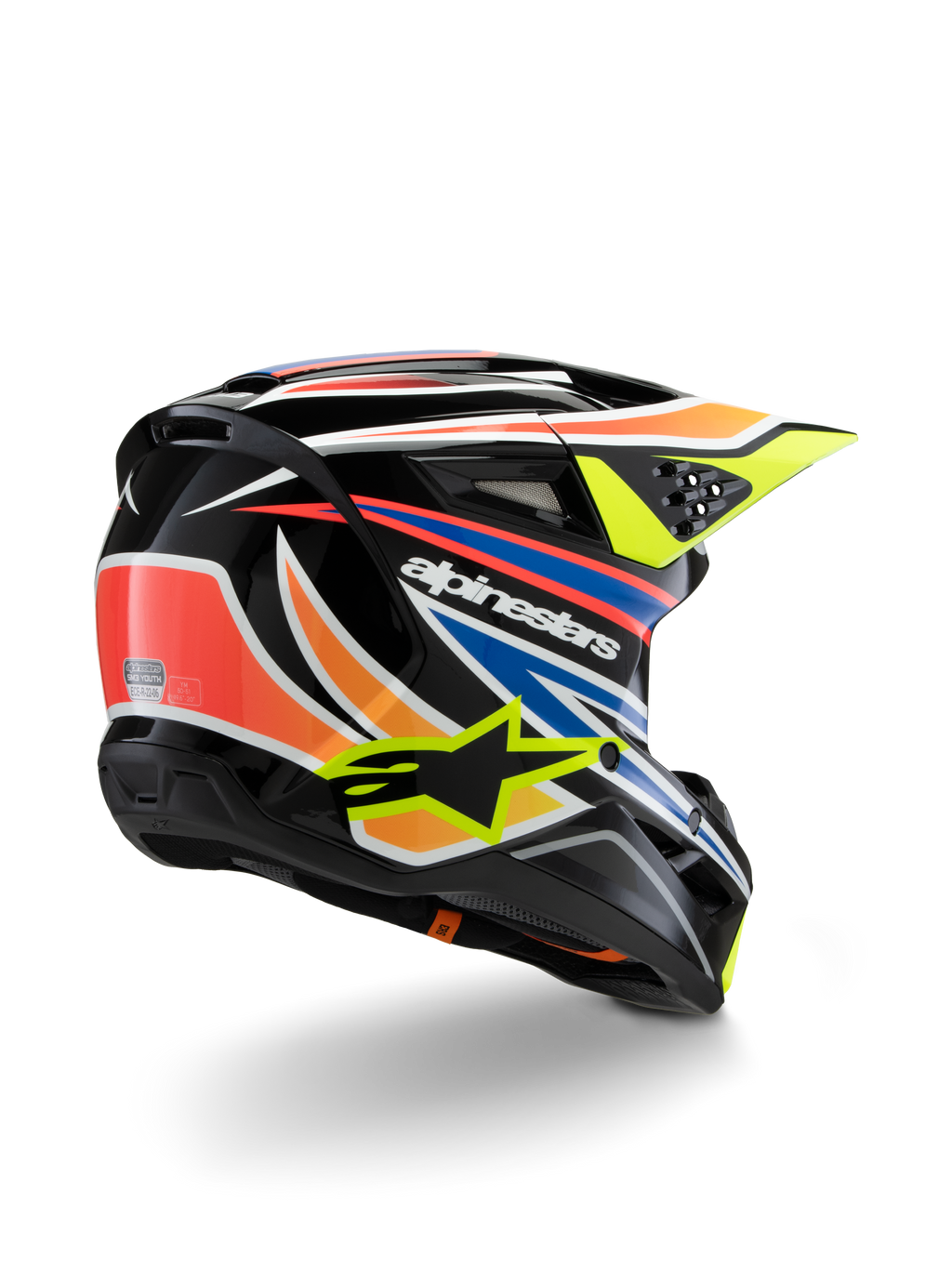 Alpinestars S-M3 Youth Wurx-hjälm, motocrosshjälm för ungdomar, svart med livfulla orangea, röda, blå och neon gula detaljer, vy snett bakifrån som visar det aerodynamiska skalet och ventilationsöppningar, glansig finish med tydlig Alpinestars-branding.
