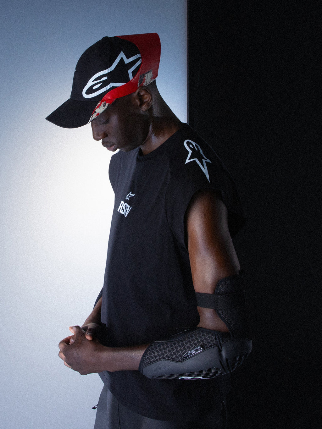 Alpinestars RSRV Tech Tank, ärmlös svart tröja med vit logotyp, unisex träningslinne, premium streetwear-kollektion, person med svart armbågsskydd