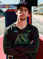 Alpinestars Ayess Csf Tee, långärmad t-shirt, svart, med grön och gul tonad AS-grafik på bröstet och ärmarna, avslappnat motorsportinspirerat streetwear buren på en racerbana