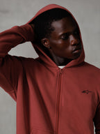 Alpinestars Essentials Ageless Zip Hoodie, tegelröd, casual lifestyle streetwear, huvan uppe med handen bakom huvudet, liten svart Astars-logotyp på bröstet, huvtröja i fleece med avslappnad passform