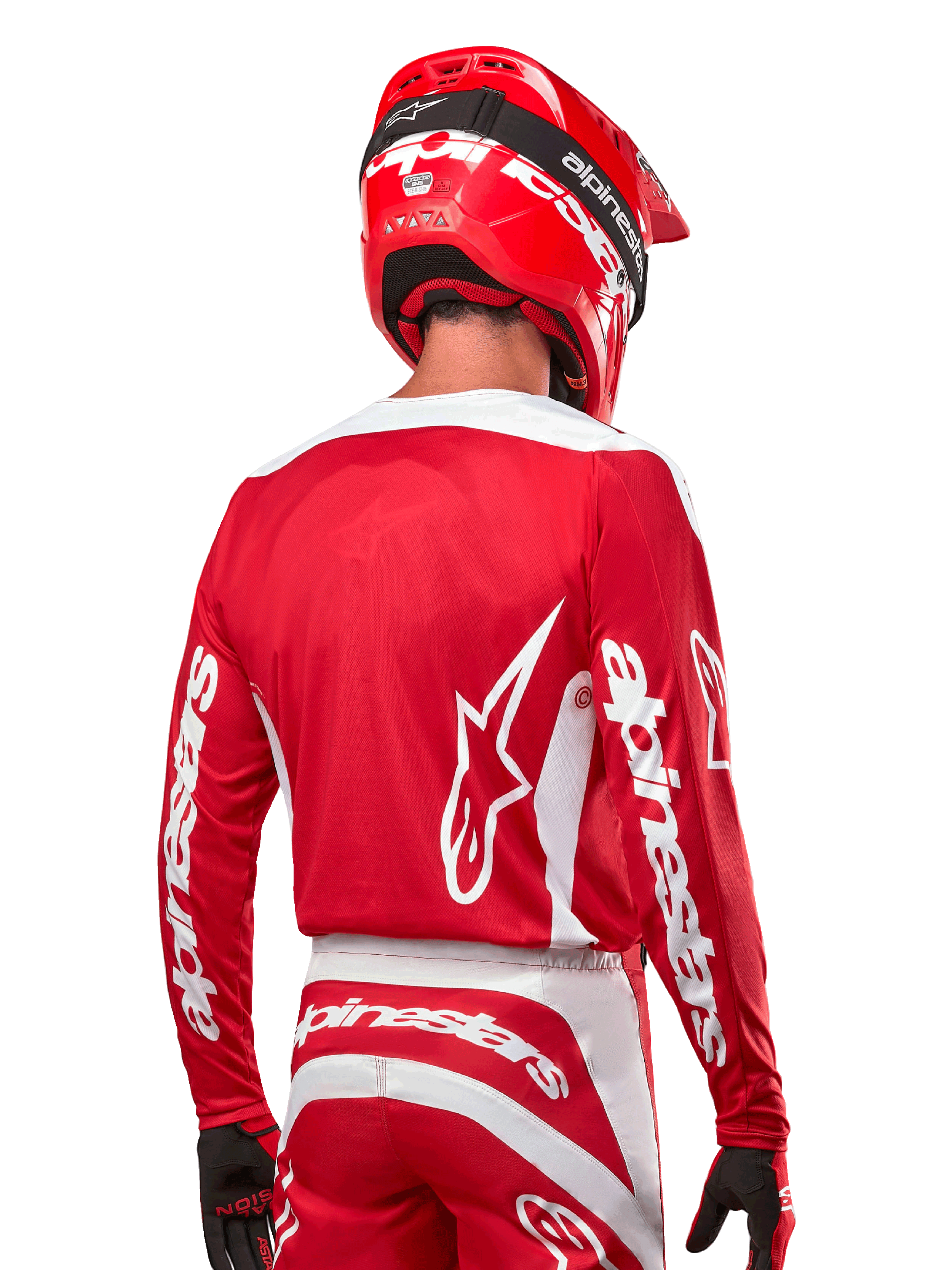Motocrossförare iklädd Alpinestars 2024 Fluid Lurv Jersey, Mars Red och vit, vy bakifrån som visar vit Alpinestars-logotyp på ryggen och branding på ärmarna, matchad med röd hjälm och svarta handskar, professionell utrustning för terrängkörning