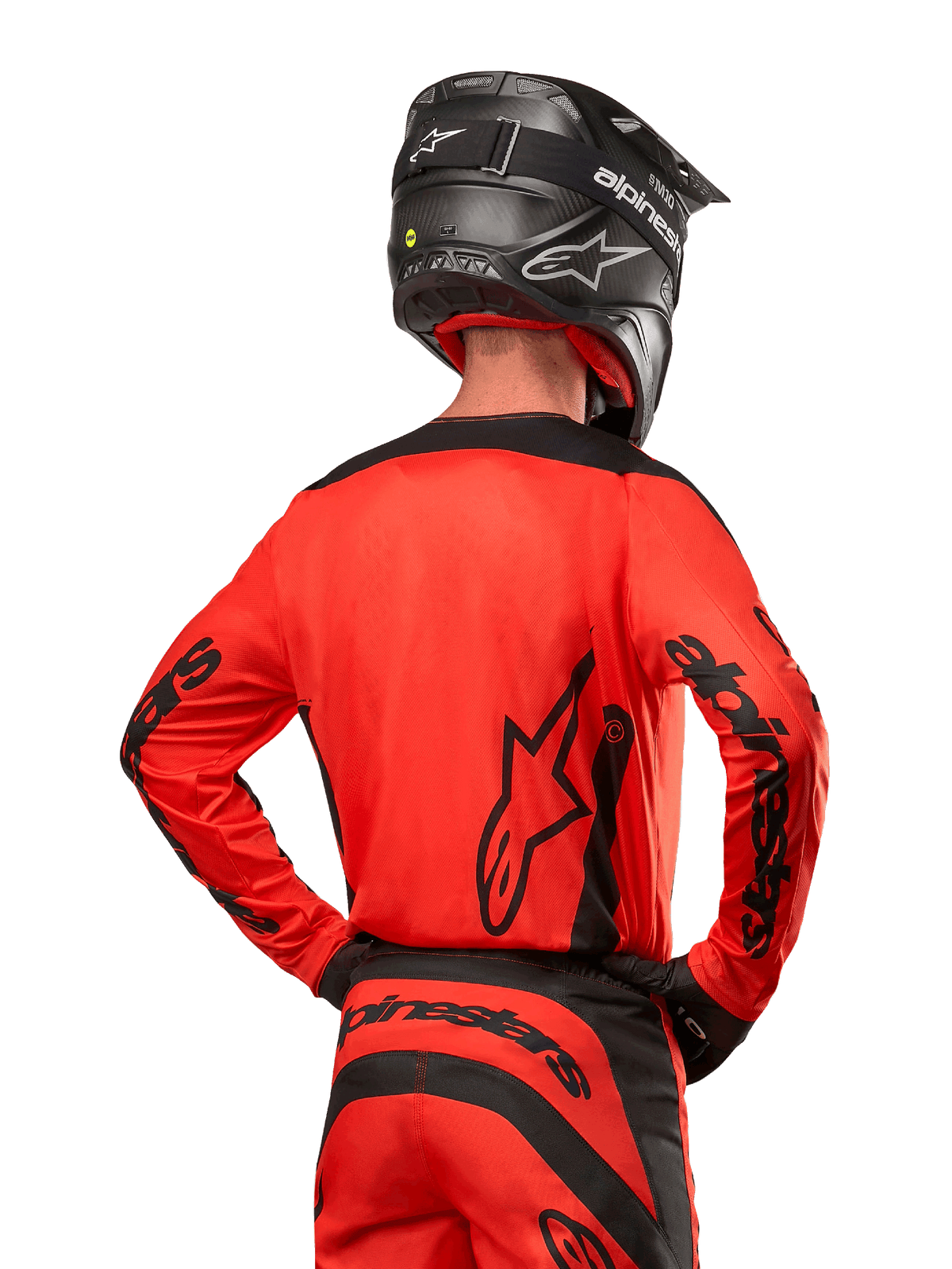 Motocrossförare sedd bakifrån bärande Alpinestars 2024 Fluid Lurv Jersey i Hot Orange och svart, med framträdande Alpinestars-logotyp på ryggen och ärmarna, kombinerad med matchande motocrossbyxor och en svart hjälm, designad för prestanda vid terrängkörning.