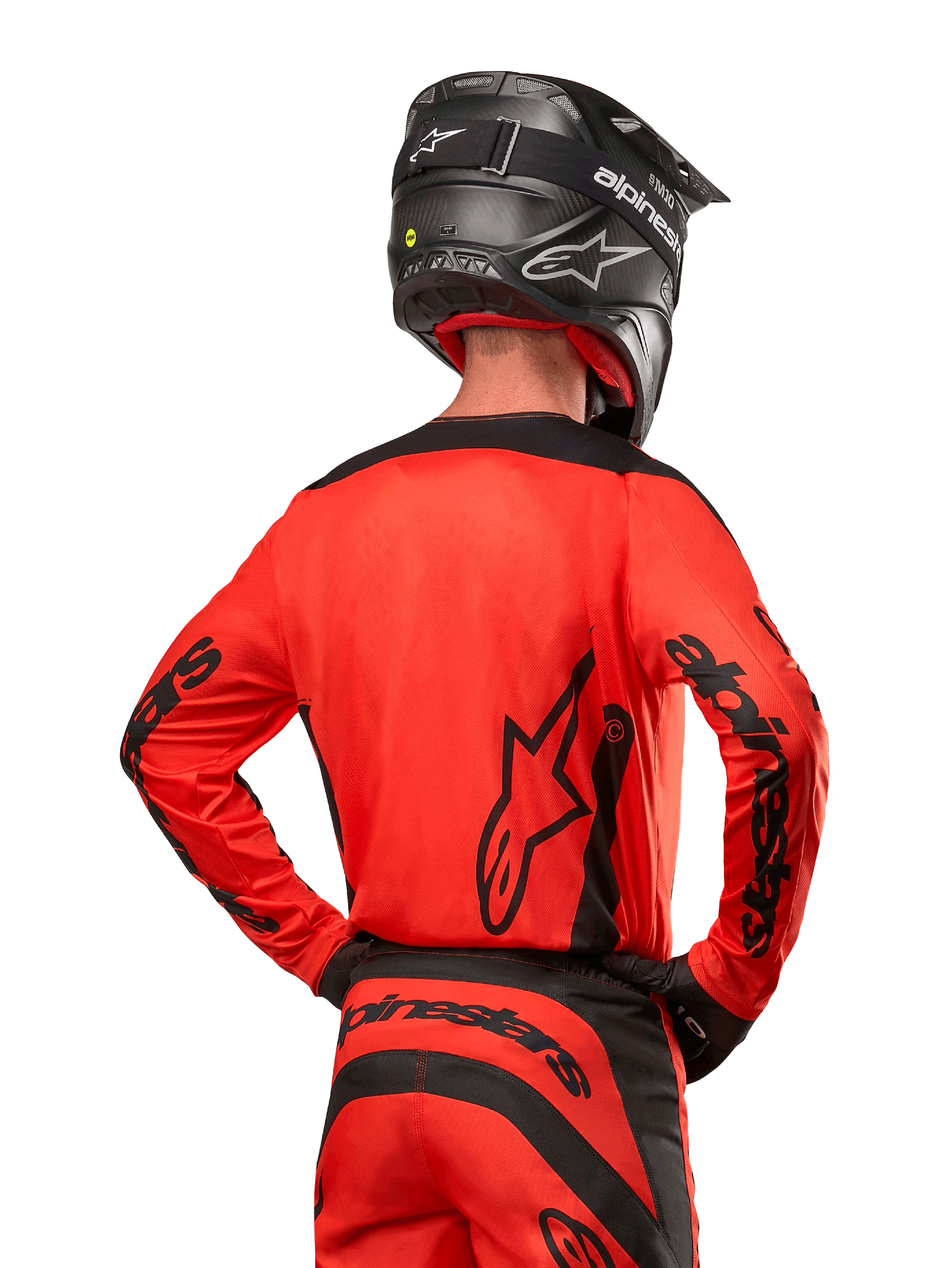 Motocrossförare sedd bakifrån bärande Alpinestars 2024 Fluid Lurv Jersey i Hot Orange och svart, med framträdande Alpinestars-logotyp på ryggen och ärmarna, kombinerad med matchande motocrossbyxor och en svart hjälm, designad för prestanda vid terrängkörning.