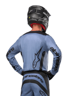 Alpinestars 2024 Fluid Lurv Jersey, Motocross Jersey, Light Blue and Black, back view of rider showing large star logo and sleeve branding, worn with a black helmet and matching off-road pants, professional racing apparel
