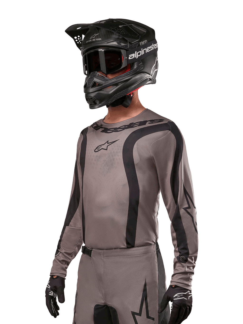 Alpinestars 2024 Fluid Lurv-tröja, motocrosströja, grå och svart, långärmad design med svängda svarta ränder och logotyper, bärs med matchande byxor och en svart motocrosshjälm, koordinerad racingutrustning för terrängkörning