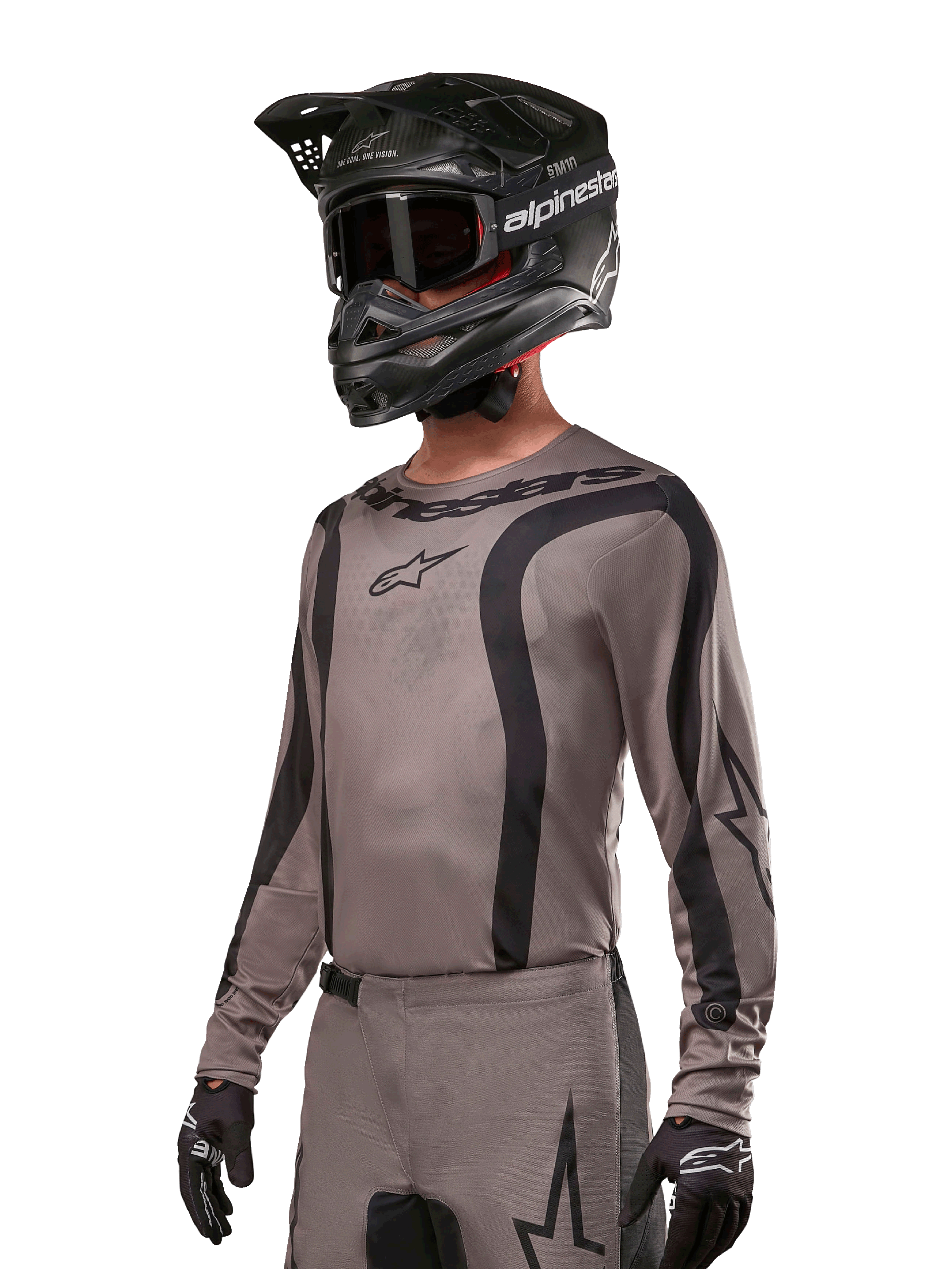Alpinestars 2024 Fluid Lurv-tröja, motocrosströja, grå och svart, långärmad design med svängda svarta ränder och logotyper, bärs med matchande byxor och en svart motocrosshjälm, koordinerad racingutrustning för terrängkörning