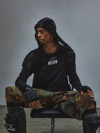 Alpinestars RSRV Nucleon SS Tee, svart t-shirt med vitt RSRV-tryck, person bär svart huvtröja, kamouflagebyxor i grönt och brunt, fingerløsa handskar med knogskydd, svarta knäskydd, urban taktisk stil