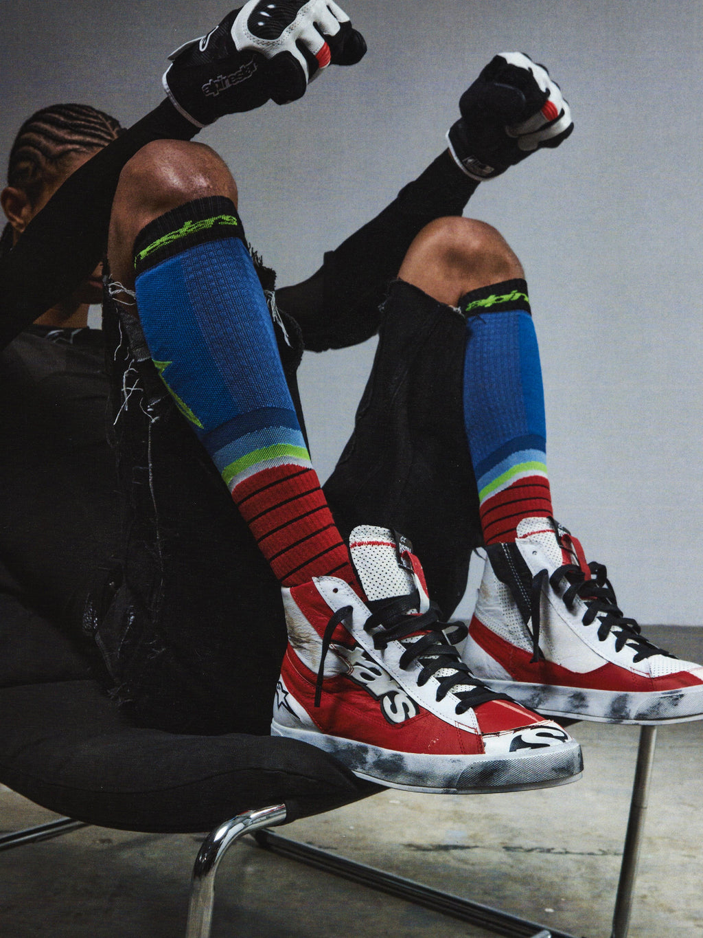 Alpinestars RSRV Legacy Shoe, röda och vita sneakers med svarta detaljer, premiumskor med logotyp, person bär färgglada strumpor och svarta handskar
