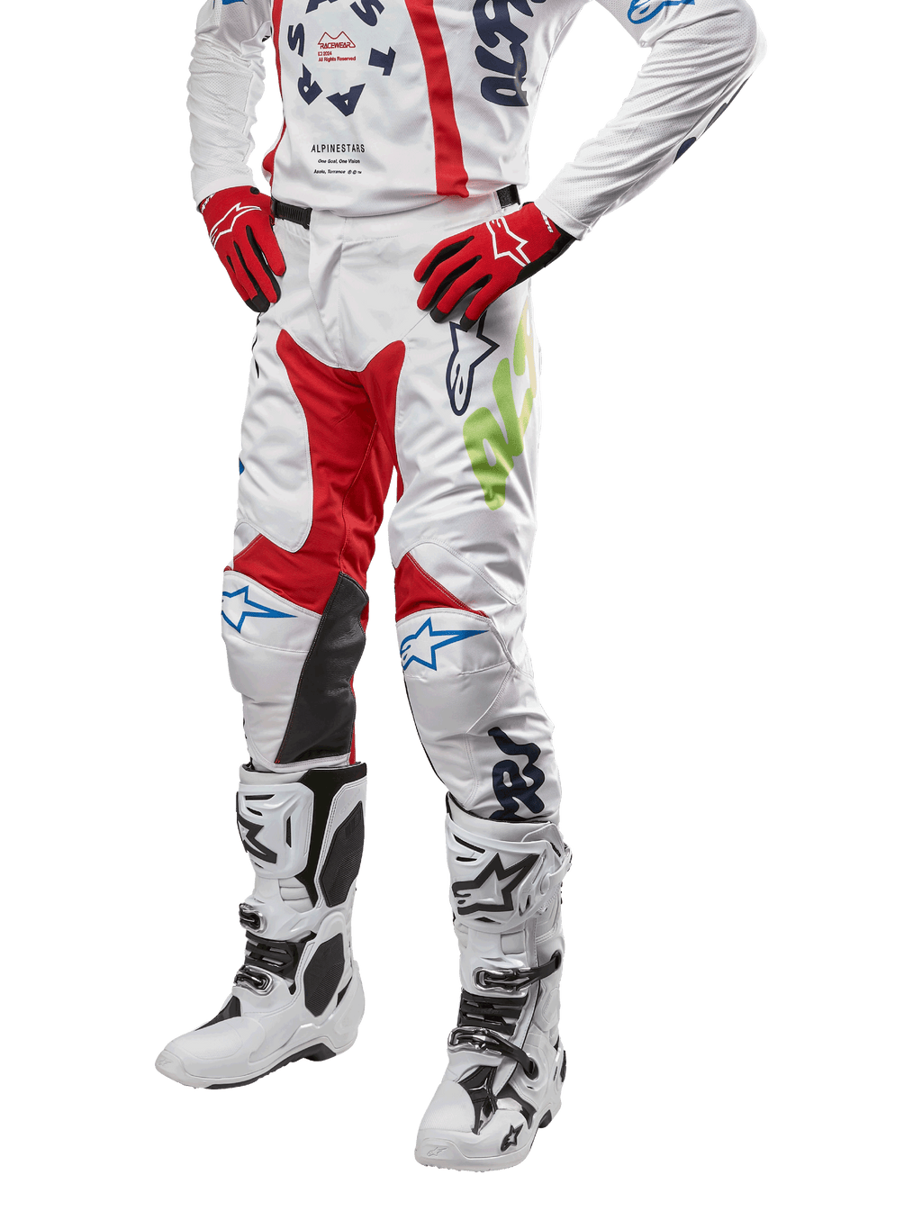 Alpinestars 2024 Racer Hana byxor, motocrossbyxor, vita med röda, blå och limegröna detaljer, skyddande design med knäpaneler i läder, bärs med matchande tröja, röda handskar och vita stövlar med spännen, sportig motorsportoutfit