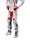 Alpinestars 2024 Racer Hana byxor, motocrossbyxor, vita med röda, blå och limegröna detaljer, skyddande design med knäpaneler i läder, bärs med matchande tröja, röda handskar och vita stövlar med spännen, sportig motorsportoutfit