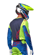Motocrossförare som bär Alpinestars 2024 Racer Hoen Jersey i Yellow Fluo och Blue Night Navy, med en röd stjärnlogotyp på ryggen, matchande motocrossbyxor och en koordinerad racinghjälm, ryggvy som visar den ergonomiska designen för terrängprestanda.