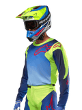 Alpinestars 2024 Racer Hoen-tröja, motocrosströja, neongul och mörkblå med röda logotyper, bärs med en matchande gul, blå och röd hjälm samt blå handskar, färgstark utrustning för terrängkörning