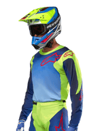 Alpinestars 2024 Racer Hoen-tröja, motocrosströja, neongul och mörkblå med röda logotyper, bärs med en matchande gul, blå och röd hjälm samt blå handskar, färgstark utrustning för terrängkörning