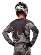 Alpinestars 2024 Racer Tactical-tröja, motocrosströja, Cast Gray Camo Magnet, ryggvy som visar grått och svart kamouflagemönster, bärs med matchande byxor och en svartvit hjälm, professionell racingutrustning för terrängkörning