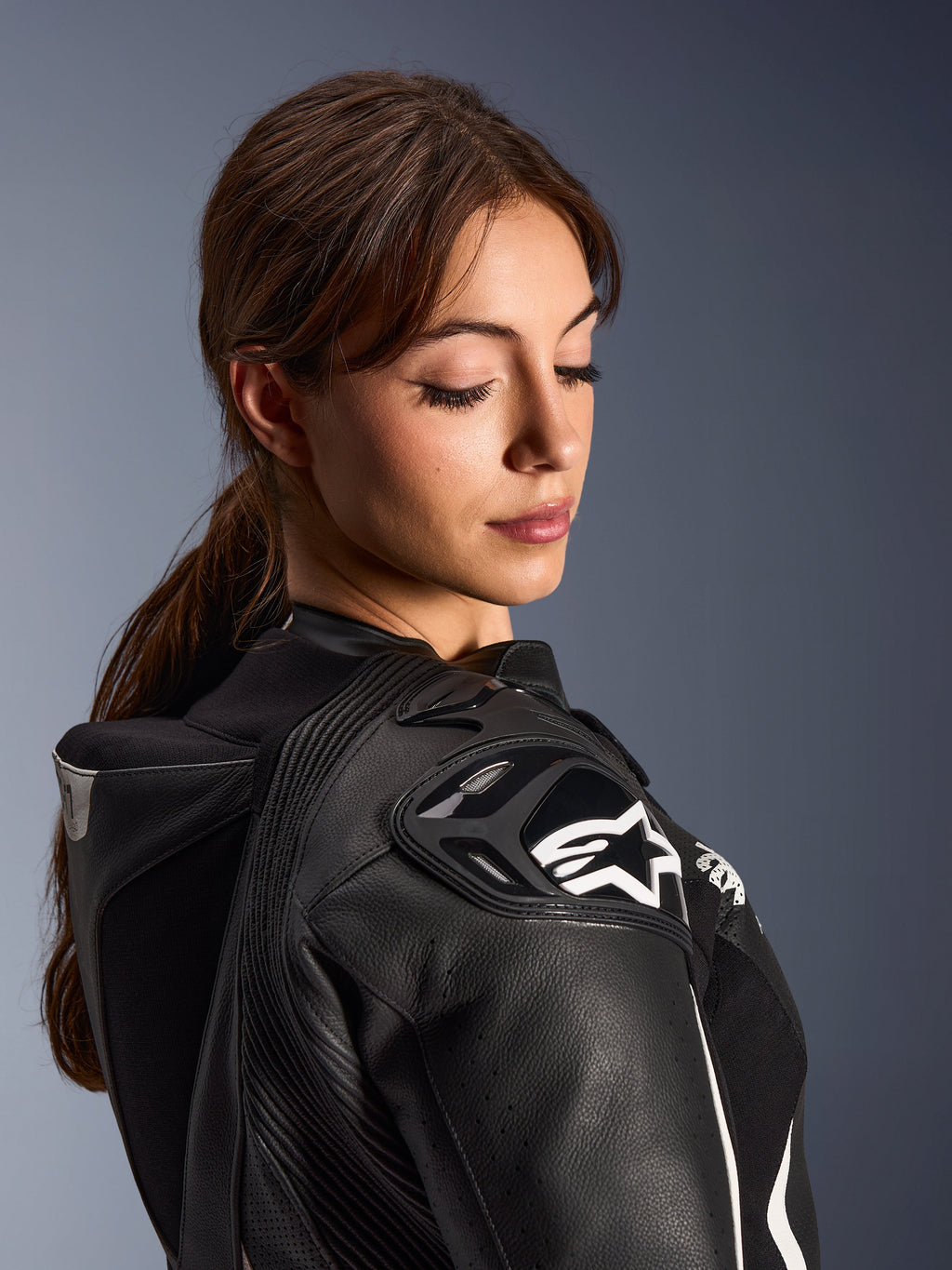 Alpinestars Stella GP-R7 2-delat läderställ för damer, närbild av axelpartiet i svart läder med DFS RR-skydd, vit stjärnlogotyp, integrerad aeropuckel och perforerade detaljer.