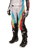 Alpinestars Women Stella 2024 Techstar Pants, Motocross Pants, Black Multicolor with diagonal red, yellow, and blue stripes, worn with black riding boots and white gloves, featuring protective black knee panels and bold branding for off-road racing.