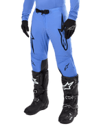 Alpinestars 2024 Supertech Dade-byxor, motocrossbyxor, ljusblå med svarta grafiska logotyper, med ventilerade perforeringar och ett magnetiskt midjespänne, kombinerade med svarta tekniska racingstövlar och handskar, professionell terrängracingutrustning