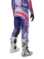Alpinestars 2024 Techstar Ocuri byxor, motocrossbyxor i lila med hot orange detaljer, vy bakifrån som visar den stora röda logotypen på sätet, vita Tech 10-stövlar, svarta handskar, prestandamaterial för motocross.