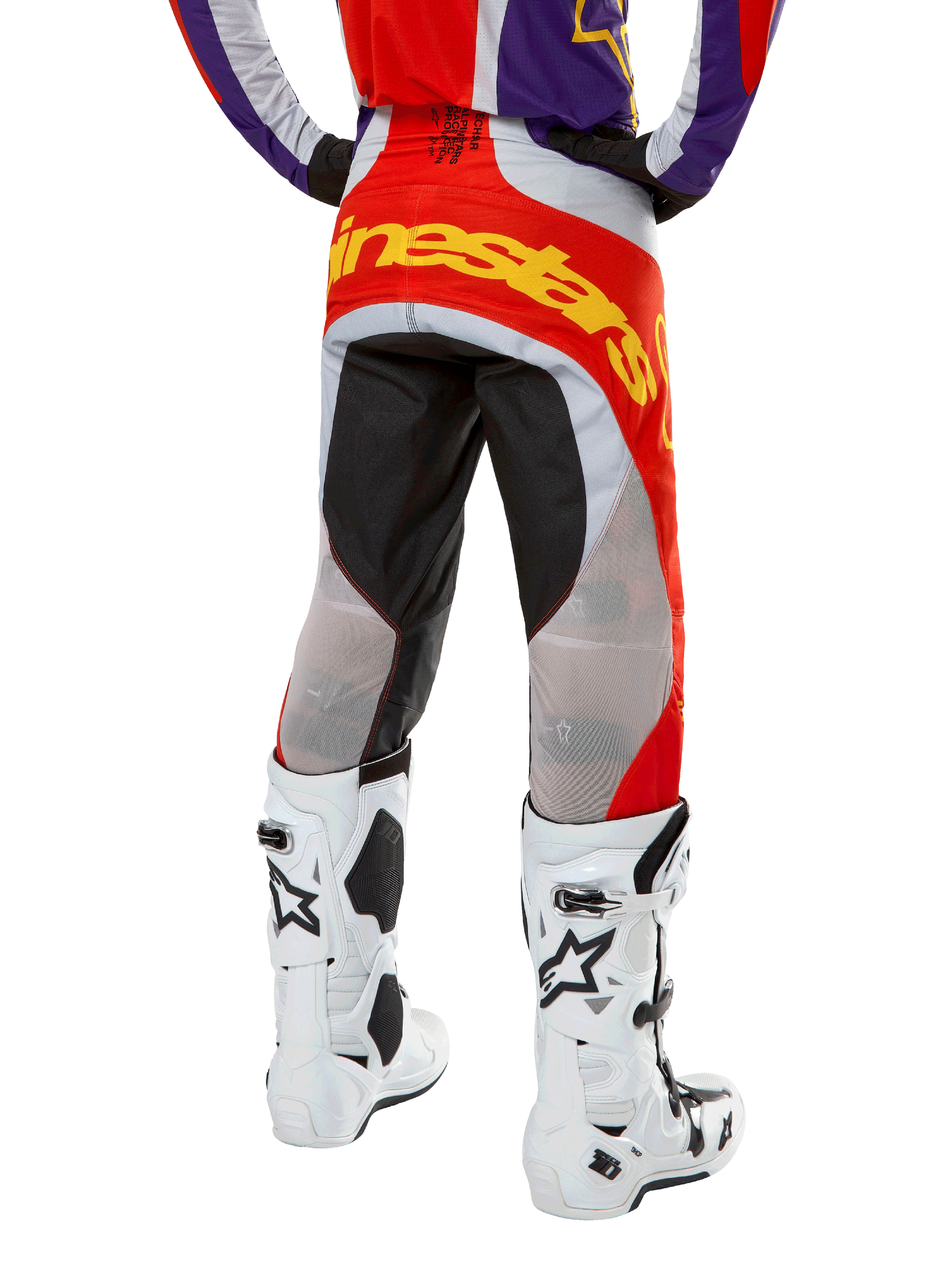 Alpinestars 2024 Techstar Ocuri Pants, Motocross Pants, Hot Orange Purple and Black, back view from the waist down, bold yellow branding across the seat, black and grey technical panels, paired with white motocross boots.