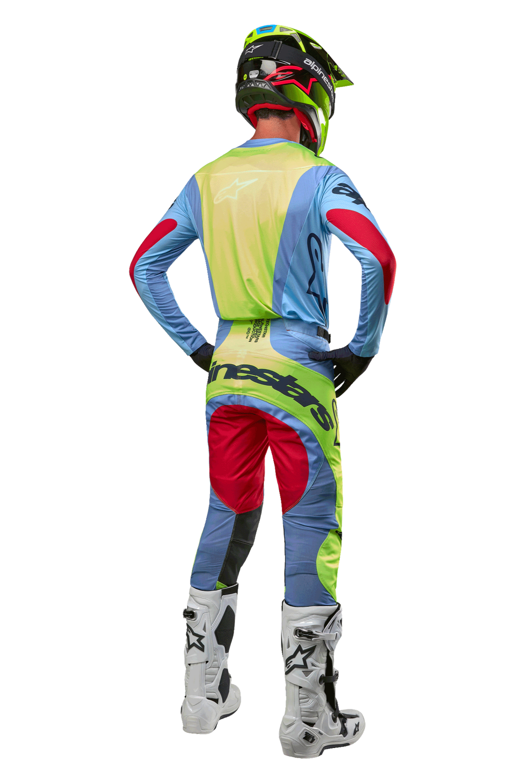 Motocrossförare sedd bakifrån iförd 2024 Techstar Ocuri-byxor och matchande tröja, ljusblå, fluorescerande gul och Red Berry, vita och svarta stövlar, svart hjälm med neondetaljer, koordinerad Alpinestars-utrustning för terrängkörning