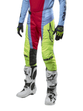 Alpinestars 2024 Techstar Ocuri byxor, motocrossbyxor, ljusblå, röda och neongula, bärs med matchande utrustning och vita stövlar, med framträdande Astars-logotyp och en racingpassform.