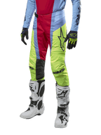 Alpinestars 2024 Techstar Ocuri byxor, motocrossbyxor, ljusblå, röda och neongula, bärs med matchande utrustning och vita stövlar, med framträdande Astars-logotyp och en racingpassform.