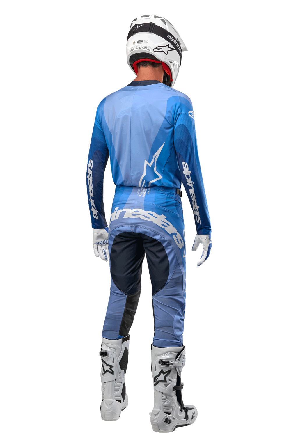 Motocrossförare sedd bakifrån bärande Alpinestars 2024 Techstar Pneuma-byxor i mörkblått och ljusblått, matchade med en blå tröja, vit hjälm, vita handskar och vita stövlar, med tydlig Alpinestars-profilering över sätet och ärmarna.