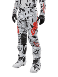 Alpinestars 2024 Techstar Rantera byxor, motocrossbyxor, Haze Gray Camo med svart och rött abstrakt mönster, bärs med matchande tröja, svarta handskar och vita motocross-stövlar, designade för högpresterande terrängkörning