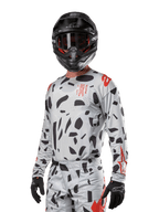Alpinestars 2024 Techstar Rantera tröja, motocrosströja, Haze Gray Camo med svarta abstrakta mönster och röda accenter, långärmad design som bärs med matchande svart hjälm och handskar, teknisk racingutrustning för terrängkörning