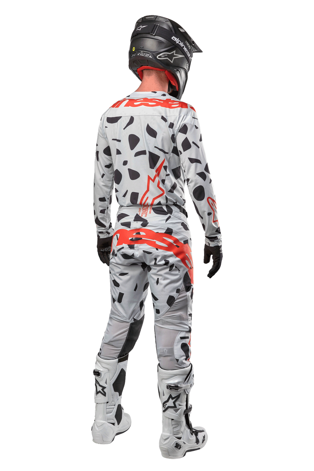 Motocrossförare sedd bakifrån iklädd Alpinestars 2024 Techstar Rantera-byxor, Haze Gray Camo med svarta fläckar och röda logotyper, matchande tröja, svart hjälm och vita stövlar, komplett outfit för terrängkörning
