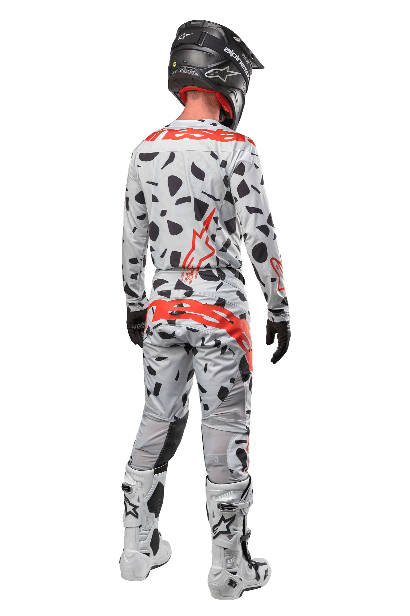 Motocrossförare sedd bakifrån iklädd Alpinestars 2024 Techstar Rantera-byxor, Haze Gray Camo med svarta fläckar och röda logotyper, matchande tröja, svart hjälm och vita stövlar, komplett outfit för terrängkörning