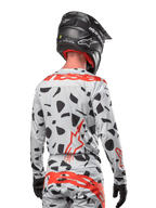 Motocrossförare sedd bakifrån i Alpinestars 2024 Techstar Rantera-tröja i Haze Gray Camo, med en ljusgrå bas med svarta grafiska fläckar och framträdande röda Alpinestars-logotyper på ryggen och axlarna, matchad med matchande byxor och en svart hjälm.
