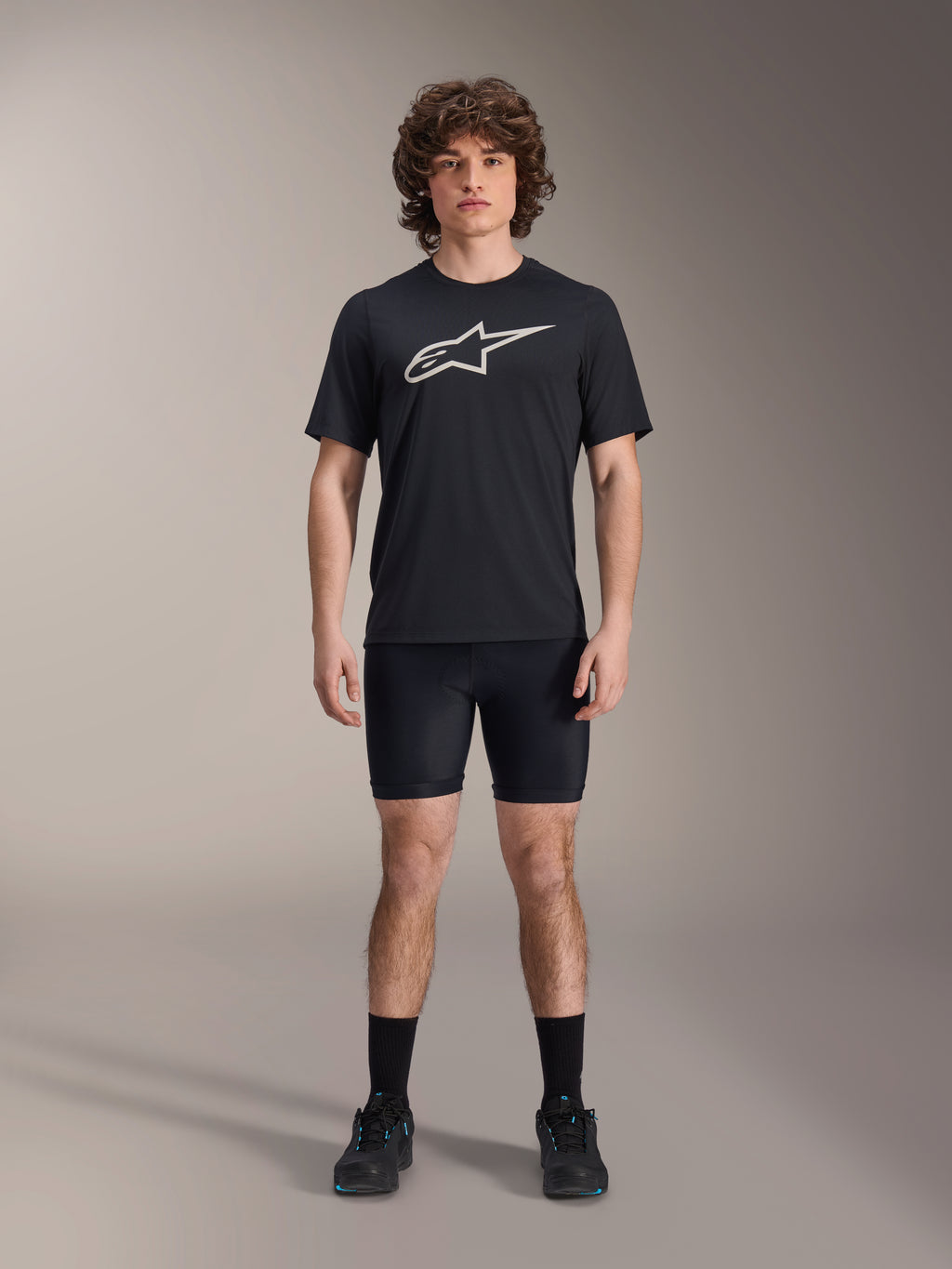Alpinestars A-Dura Liner Shorts, svarta cykelinnerbyxor, bärs av en modell med en svart t-shirt med Alpinestars-logotyp och svarta cykelskor, tight passform för MTB-prestanda och komfort i sadeln.