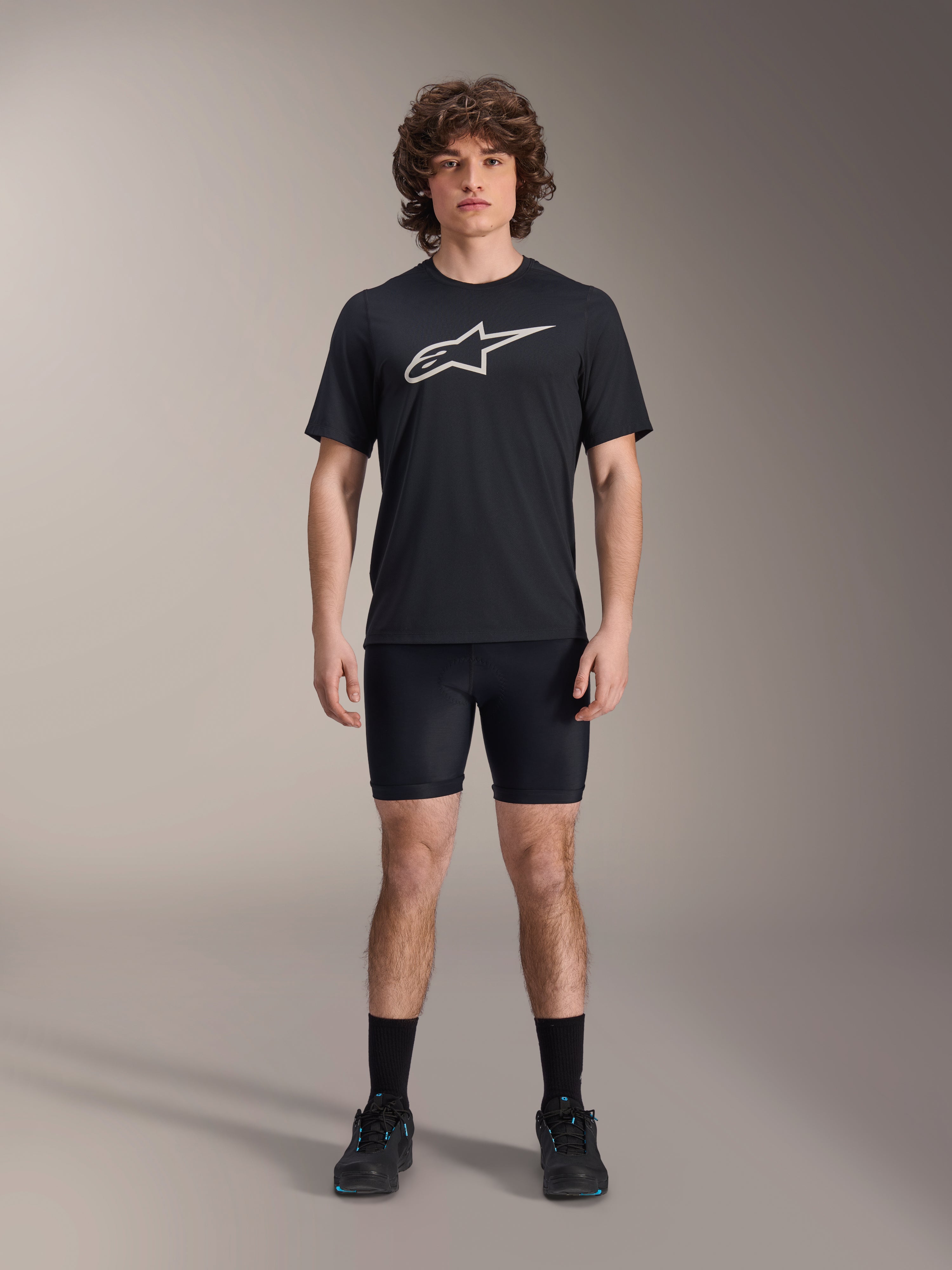 Alpinestars A-Dura Liner Shorts, svarta cykelinnerbyxor, bärs av en modell med en svart t-shirt med Alpinestars-logotyp och svarta cykelskor, tight passform för MTB-prestanda och komfort i sadeln.