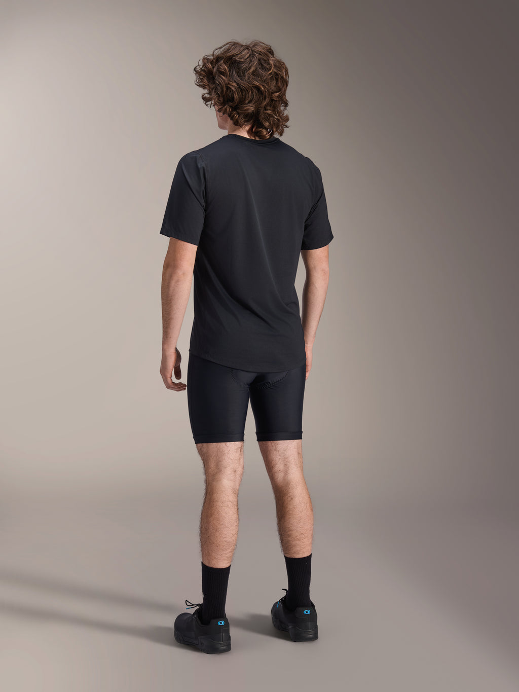 Alpinestars A-Dura Liner Shorts, svarta cykel-innerbyxor, baksida på modell, åtsittande stretchtyg med synliga sömmar för chamois-vaddering, kombinerat med en svart t-shirt och cykelskor, mountainbike-kläder